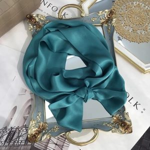 Solid dark green mulberry silk skinny scarf tied in a bow on a vintage frame