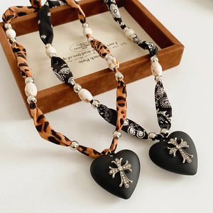 Detail of heart pendants with rhinestone crosses on leopard and paisley fabric straps