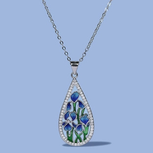 Detail of silver drop pendant with blue enamel flowers and sparkling zircon border