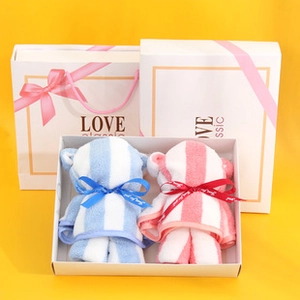 Close-up of cute bear-shaped striped towels in matching pink and blue gift boxes