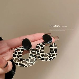 Fashionable leopard print acrylic hoop earrings with a black geometric stud on a model