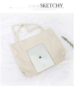 Macro detail of a beige canvas tote bag shown next to an iPad for size comparison