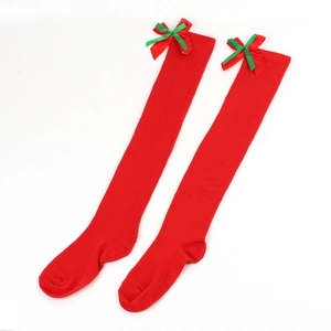 Detail showing red knitted over-knee socks with green bow and Christmas holiday texture