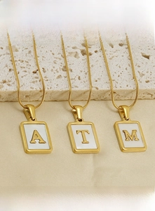 Détail de pendentifs rectangulaires en acier doré avec lettres sur chaîne serpent