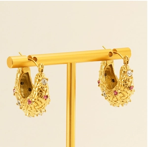 Detail of 18K gold-plated hoop earrings featuring basket-weave texture and pink crystals