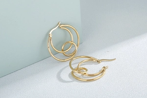 Close-up of golden multi-layer circular knot earrings with polished stainless steel finish