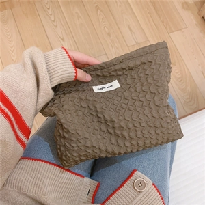 Vue détaillée de la trousse à maquillage marron plissée avec une petite étiquette blanche