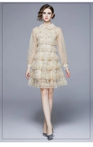 Détail de la robe en dentelle champagne avec jupe à volants et broderie florale