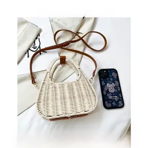 Top view of handmade semi-circle straw bag with brown leather handles and inner drawstring pouch