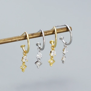 Close-up of s925 silver stud earrings with gold and silver finishes and zircon drops