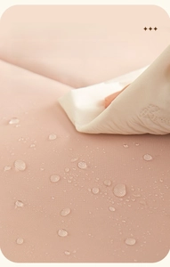 Close-up of waterproof pink fabric with water droplets showing stain resistance