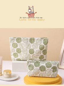 Detail view of two canvas makeup bags with green leaf patterns and zipper closure