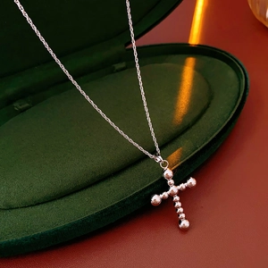 Détail du collier pendentif croix perlée dans un luxueux coffret cadeau en velours vert