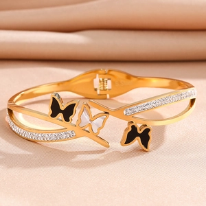 Detail of gold butterfly bracelet with white zircon and black enamel on pink silk