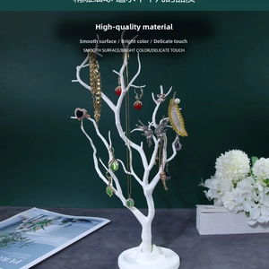 White tree-shaped jewelry organizer stand with various gold necklaces and earrings