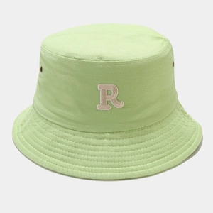 Close-up of beige R letter embroidery and twill cotton texture on light green bucket hat