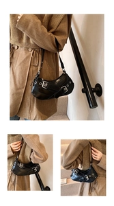 Detail of black punk crescent underarm bag with metal buckles and silver eyelets