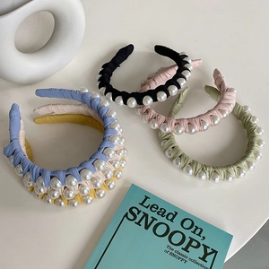 Flat lay of colorful fabric headbands with artificial pearls on a minimalist background