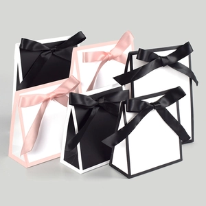 Detail showing trapezoid gift bags with elegant ribbon bows in black, white, and pink