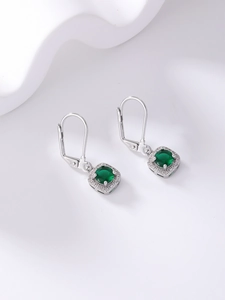 Macro detail of silver drop earrings featuring square green emerald-cut zircon stones
