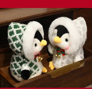 Close-up of cute plush penguins in winter coats with red bows and golden bells