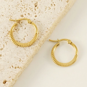 Detail of 18K gold-plated titanium hoop earrings with textured stripes on stone base