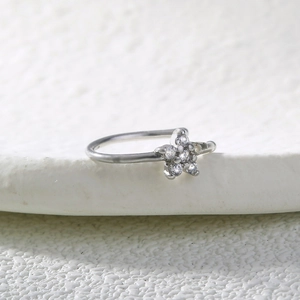 Macro shot of a silver star nose ring with shiny zircons on a white stone background