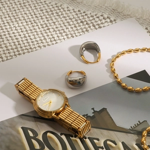 Close-up of geometric two-tone stainless steel earrings and jewelry on magazines