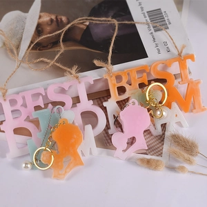 Dettaglio dei ciondoli in resina Best Mom con perle decorative e anelli d'oro