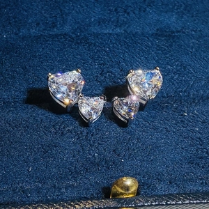 Macro shot of silver heart studs with clear cubic zirconia in a blue velvet box