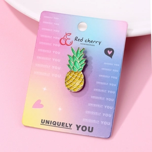 Detailed view of yellow pineapple enamel pin on colorful brand display card