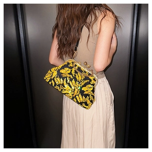 Detail of yellow and black sequin shell bag featuring a gold metallic clasp on model