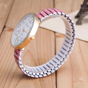 Close-up of pink floral stretch band and golden watch case on wooden background