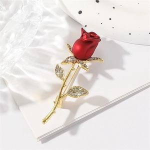 Elegant red rose brooch with gold stem and sparkling crystals on textured surface