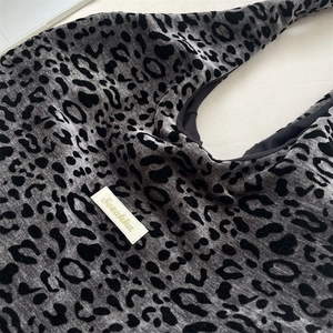 Detail of gray leopard print flocking fabric and brand label on a stylish tote bag
