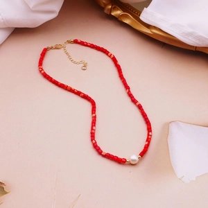 Detailed shot of red seed bead necklace featuring a central white pearl and gold clasp