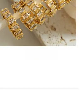Macro view of gold jewelry with channel-set rectangular zircon on a stone surface