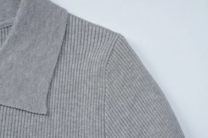Detailed view of the grey ribbed knit fabric texture and the polo collar stitching