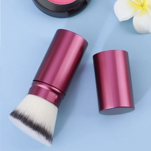 Macro view of portable flat-head makeup brush with metallic rose red handle and cap