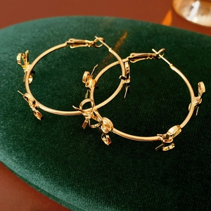 Close-up of golden hoop earrings with multiple bows on dark green velvet padding