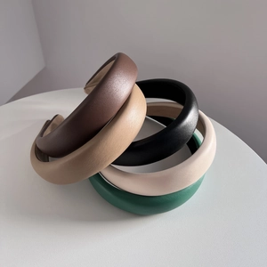 Five chic padded PU leather headbands in vintage colors on a minimalist table