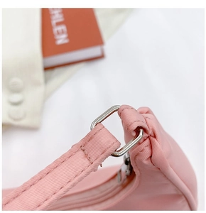 Detail of pink nylon shoulder bag showing silver metal buckle and matching zipper closure