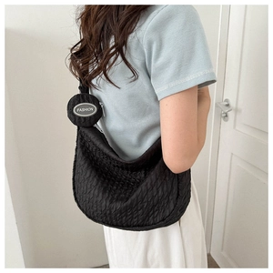 Detail of black pleated nylon crossbody bag with matching round coin purse on a model