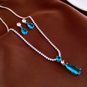 Luxuriöses silberfarbenes Schmuckset mit blauen Edelsteinen auf braunem Satinstoff