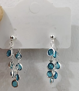 Detail of silver tassel earrings featuring sparkling blue rhinestones on a white card