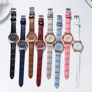 Flat lay of colorful quartz watches with leather straps and gold cases in various shades
