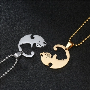 Detail of yin-yang cat necklaces for couples in silver and gold tone on a black background