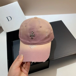 Close-up of pink distressed cotton baseball cap with silver metal cross and ripped brim