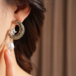 Detail of vintage gold star and moon earrings with baroque pearl and crystal on model