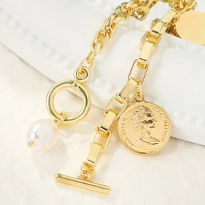 Detail of vintage gold toggle clasp bracelet featuring baroque pearl and coin charm